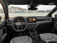 Interieur van een Seat Ibiza met grijs-zwarte bekleding, dashboard en stuur, met zeezicht.