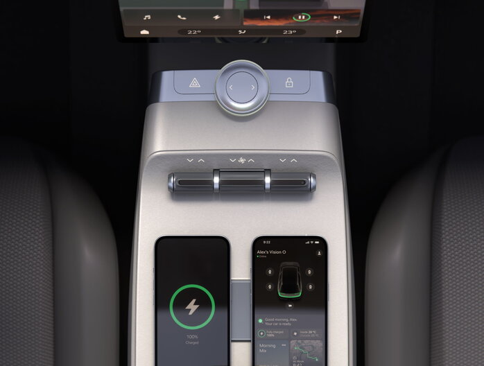 Skoda Vision O auto interieur met zilveren console, draadloos opladende smartphones en een modern scherm.