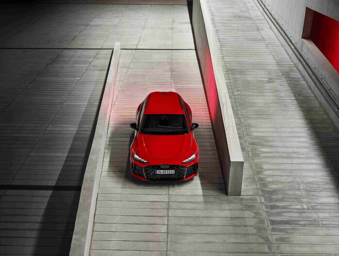 Uniek bovenaanzicht van de rode Audi RS5 Avant die een helling in een parkeergarage oprijdt.