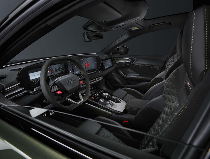 Blik in het interieur van de Audi RS5 vanaf het bestuurdersportier, met focus op luxe en sportiviteit.
