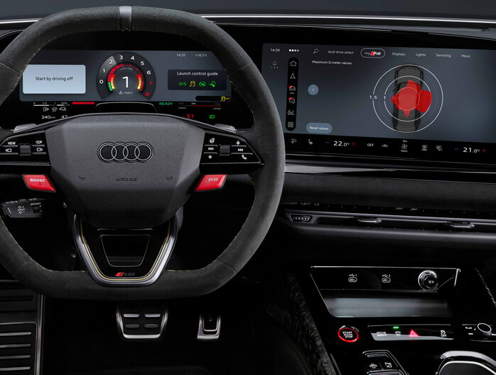Interieur van de Audi RS5 met digitaal Virtual Cockpit display, RS sportstuur met rode RS knop en groot MMI touchscreen met Audi Drive Select en performance weergave.