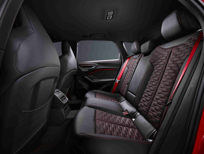 Interieur van een Audi RS5 met zwarte sportstoelen, rode stiksels en rode veiligheidsgordels.