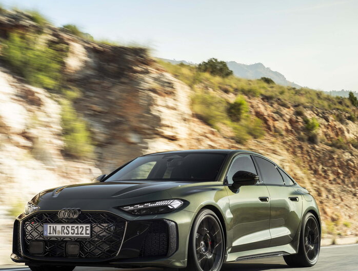 Vooraanzicht groene Audi RS5 die dynamisch over een bergweg rijdt onder een stralende zon