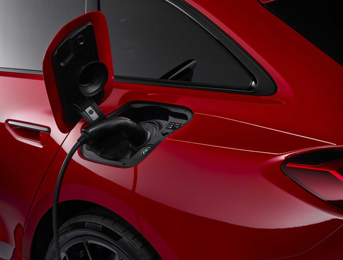 Rode Audi RS5 elektrisch voertuig laadt op, met close-up van de laadpoort en velg.