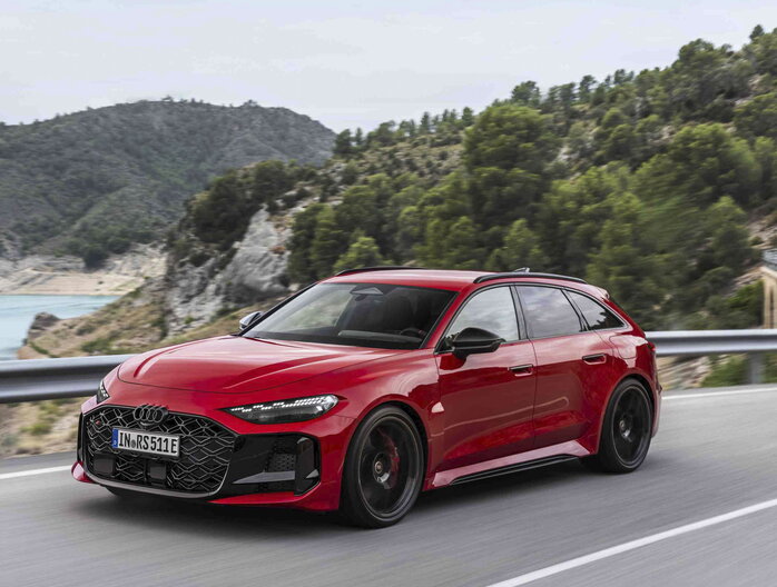 Rode Audi RS5 avant rijdt dynamisch over een bergweg met panoramisch zicht