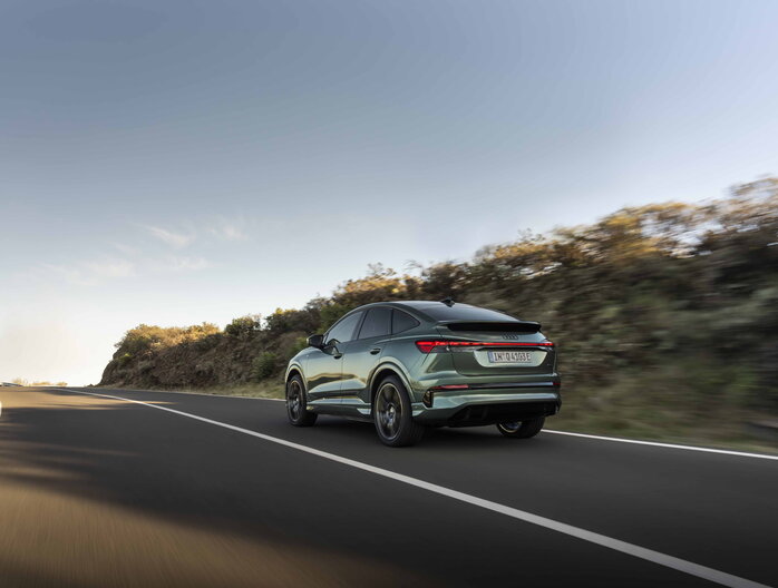 Audi Q4 e-tron rijdend op een bochtige weg in zijaanzicht