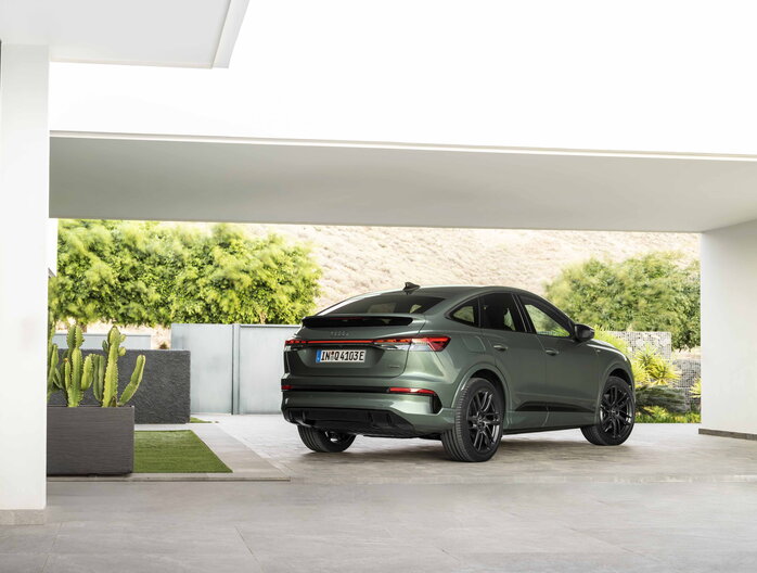 Donkergroene Audi Q4 SUV van achteren geparkeerd op moderne oprit met zwarte velgen.