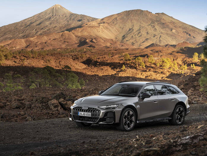 Audi A6 Allroad in donkergrijs voor imposante vulkaan, toont avontuurlijk design.