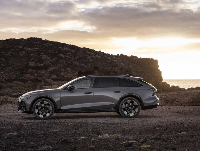 Zijaanzicht van de donkergrijze Audi A6 Allroad stationwagon met robuuste details bij zonsondergang.