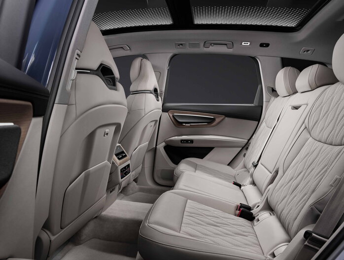 Ruime Audi Q7 achterbank met lichtbeige lederen bekleding en panoramisch dak.