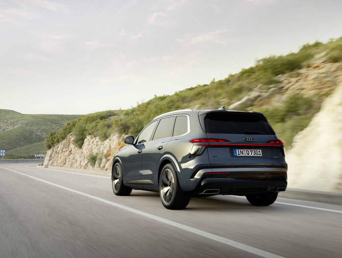 Een slanke donkerblauwe Audi Q7 rijdt op een kronkelende bergweg.
