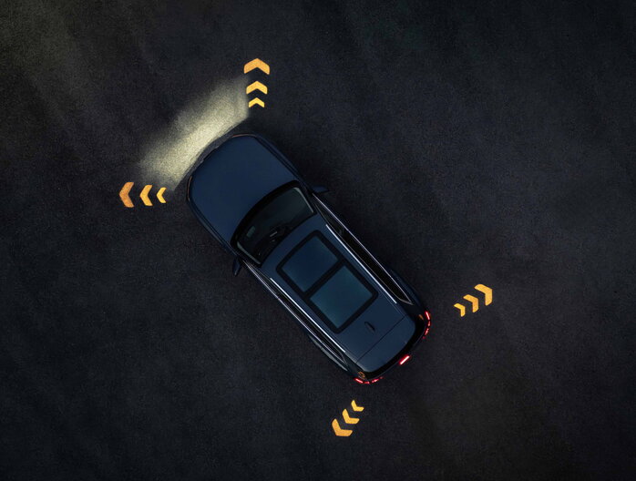 Een donkerblauwe Audi Q7 toont innovatieve parkeerassistentie met lichtpijlen op donker wegdek.