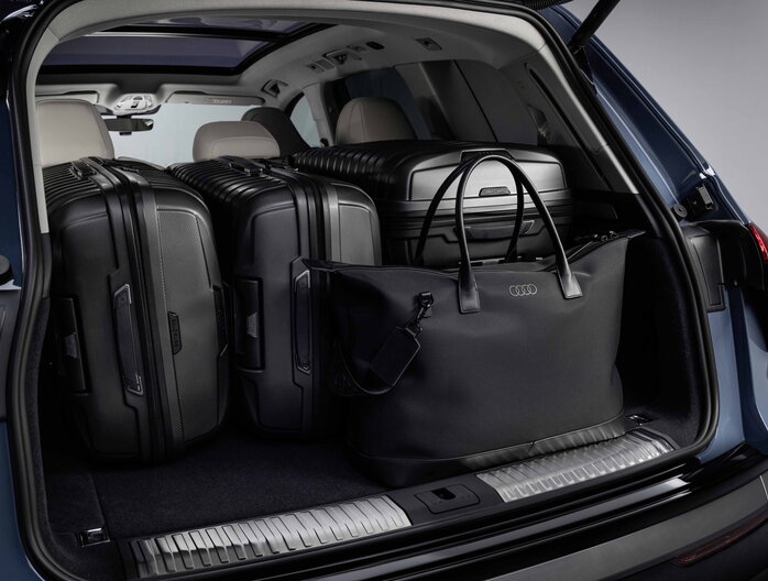 De ruime Audi Q7 kofferbak is gevuld met diverse zwarte reiskoffers en tassen.
