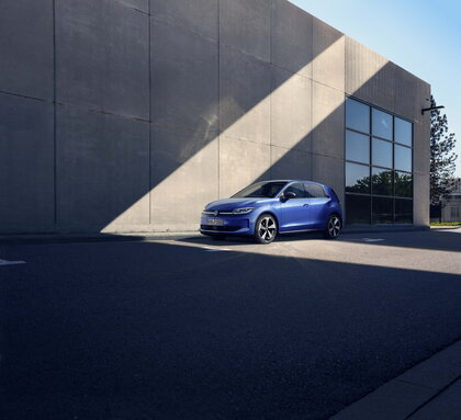De blauwe Volkswagen ID.Polo staat geparkeerd voor een modern betonnen gebouw.