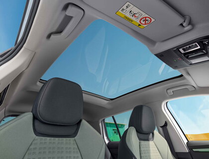 Interieur van de witte Škoda Epiq met panoramisch glazen dak en groen-grijze stoelen.