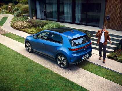 Blauwe Volkswagen Id.Polo elektrisch geparkeerd voor modern huis met man.