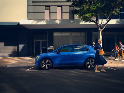 Blauwe Volkswagen Id.Polo in stadsomgeving geparkeerd naast trottoir met mensen.