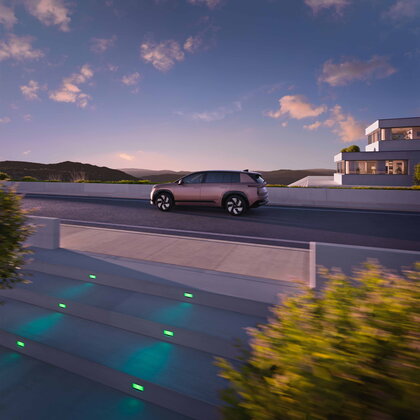 Škoda Peaq zijkant bij zonsondergang boven trappen aan een villa