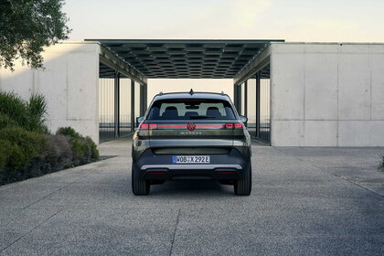 Donkergroene Volkswagen Id.Cross toont slank achteraanzicht bij modern gebouw, klaar voor actie.