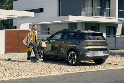 Een man laadt boodschappen uit de groene Volkswagen ID.Cross bij zijn huis.