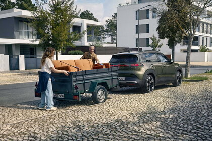 De groene Volkswagen ID.Cross trekt een aanhanger met een oranje bankstel.