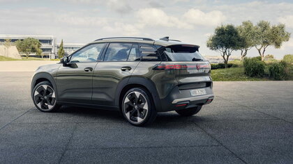 Volkswagen Id.Cross in donkergroen met stijlvol zijaanzicht parkeert buiten, natuurlijke omgeving.