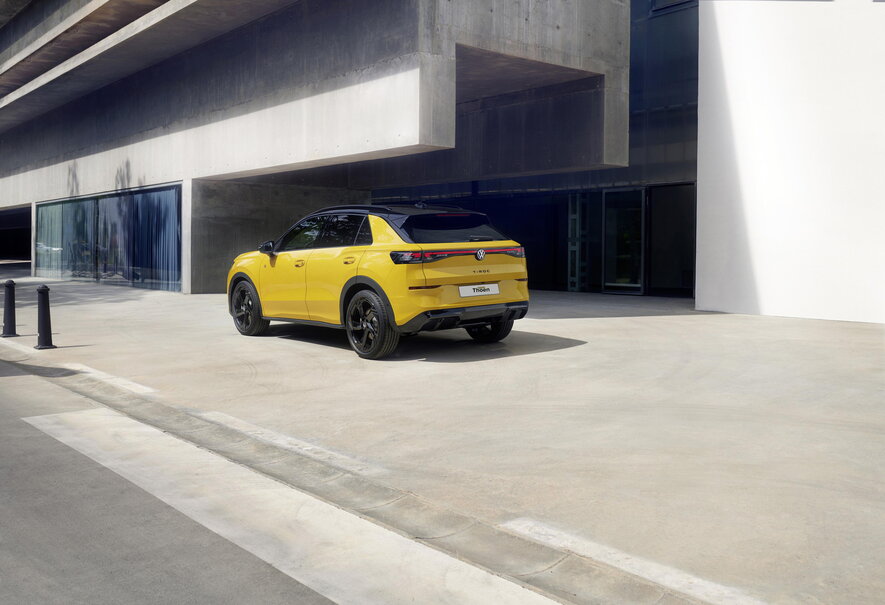 Achteraanzicht van de gele Volkswagen T-Roc geparkeerd bij een modern gebouw.