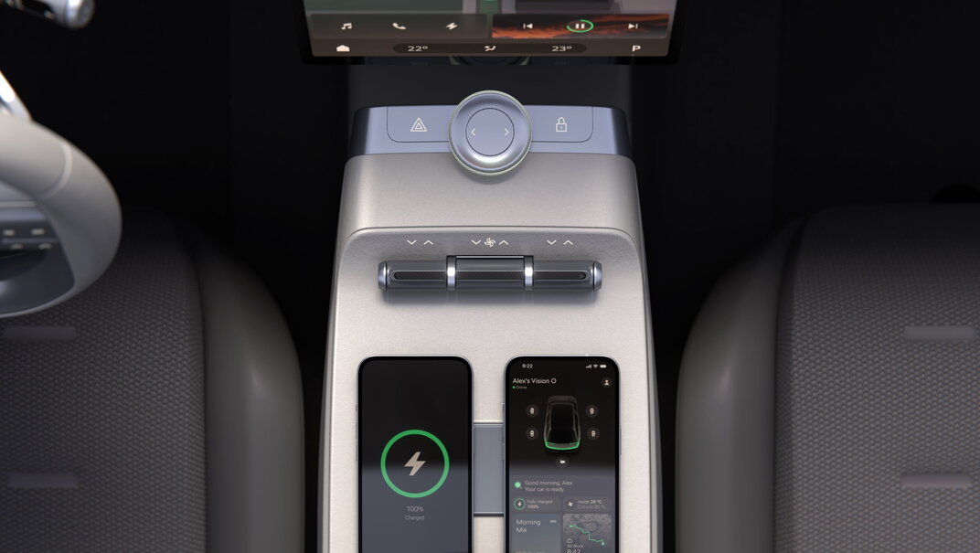 Skoda Vision O auto interieur met zilveren console, draadloos opladende smartphones en een modern scherm.