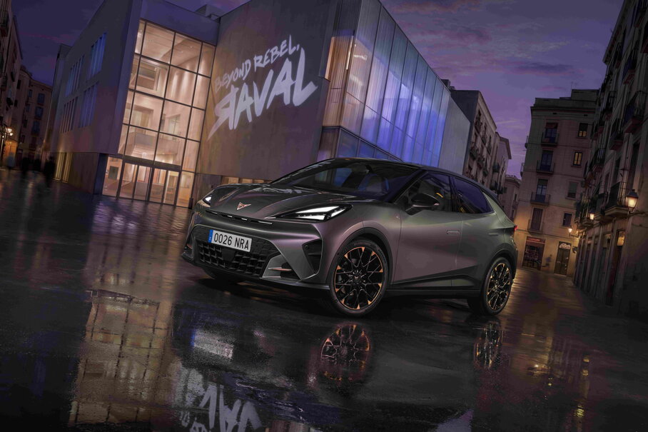 Driekwart vooraanzicht van de nieuwe elektrische CUPRA Raval in de kleur Plasma, geparkeerd op een nat wegdek in een stedelijke omgeving bij nacht met reflecties.