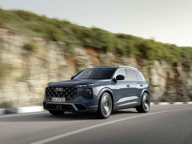 Donkerblauwe Audi Q7 SUV rijdt langs een kronkelende bergweg.