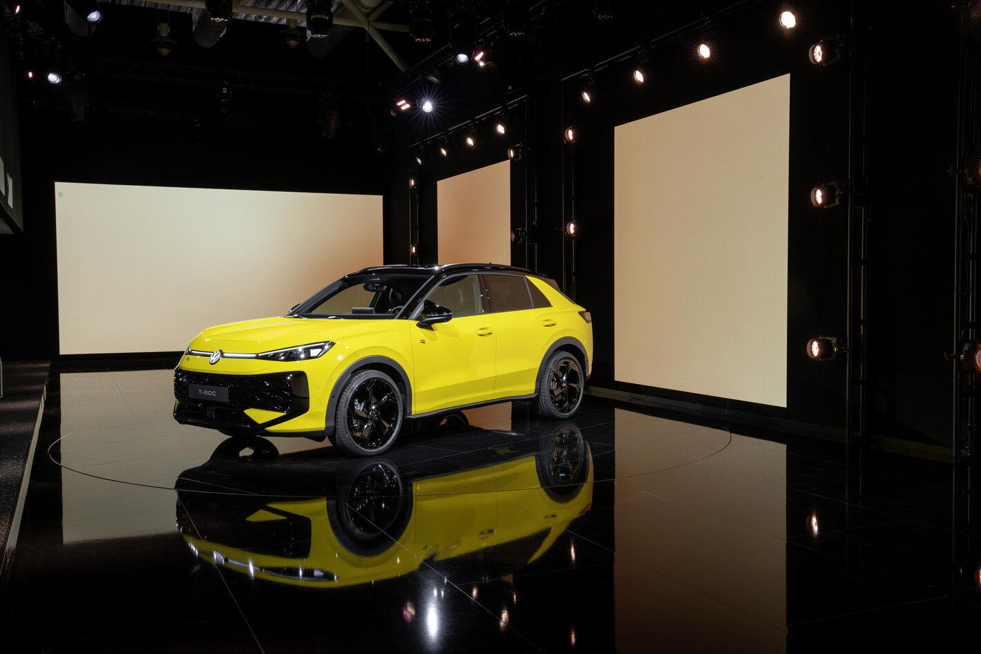 Gele Volkswagen T-Roc op een podium met zwarte accenten en moderne LED-verlichting