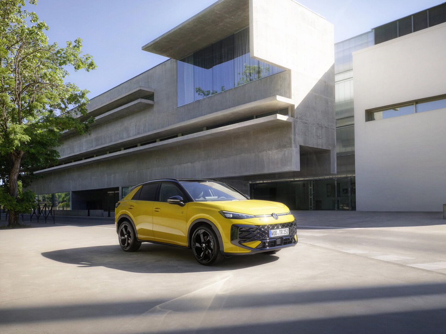 Gele Volkswagen T-Roc voor een modern architecturaal gebouw
