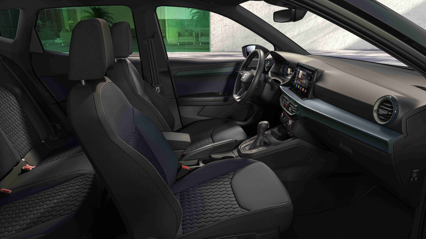 Modern interieur van de Seat Arona met donkere stoffen stoelen en centraal infotainmentscherm.Modern interieur van de Seat Arona met donkere stoffen stoelen en centraal infotainmentscherm.