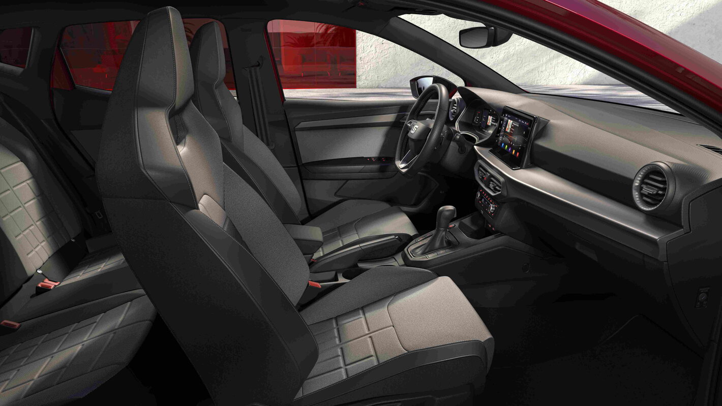 Gedetailleerd interieur van de rode Seat Ibiza, inclusief tweekleurige stoelen en modern dashboard.