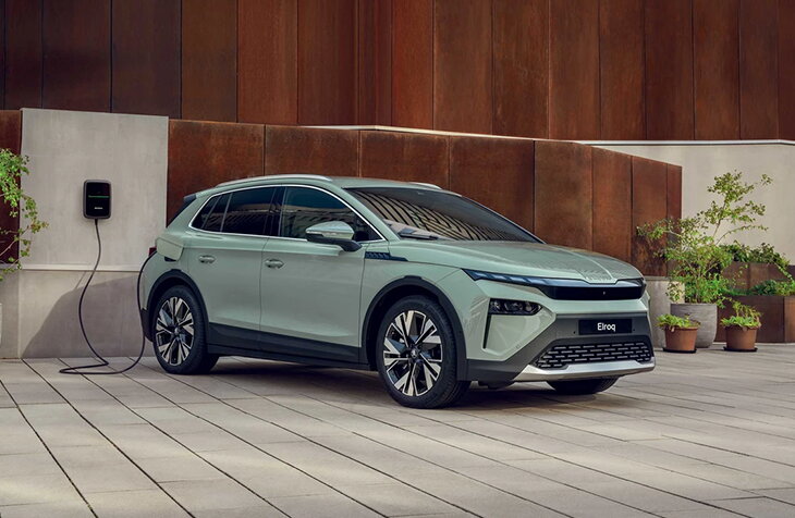 Škoda Elroq elektrische SUV aangesloten op een thuislaadpaal in een moderne stadsomgeving.