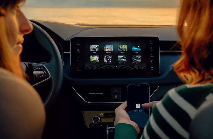 Twee personen in een Škoda Kamiq bedienen het infotainmentsysteem terwijl Apple CarPlay wordt verbonden via smartphone.