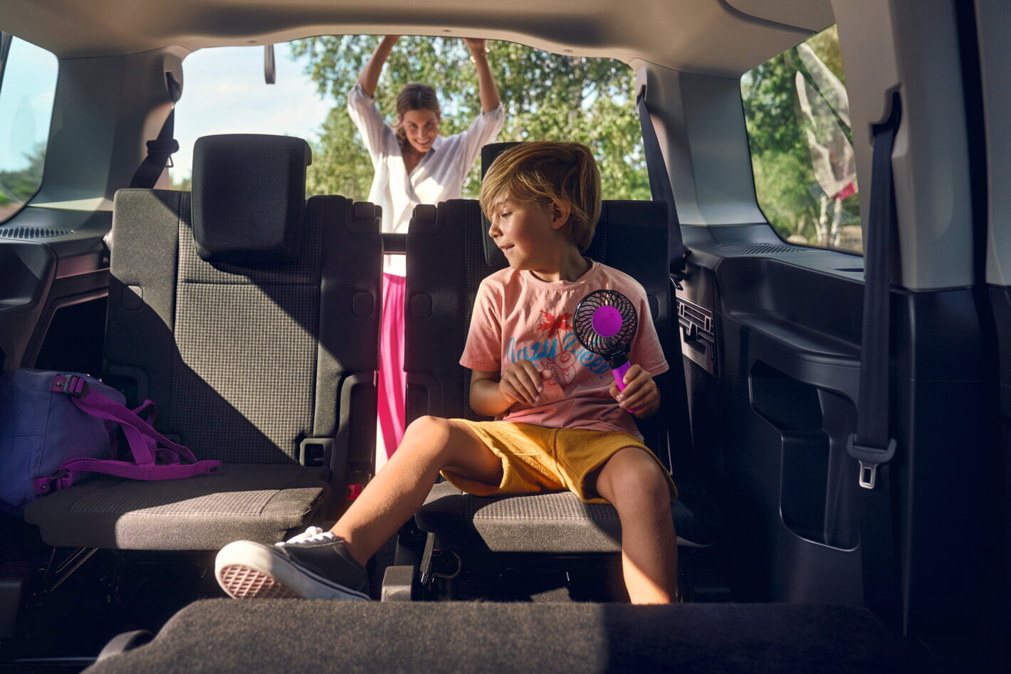 Volkswagen Caddy interieur kind op achterbank en mama doet koffer open