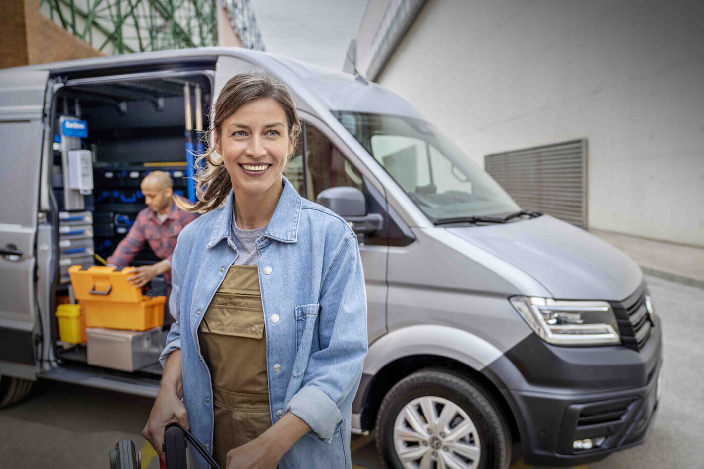 Volkswagen crafter grijs met man in cargo ruimte en lachende vrouw op voorgrond