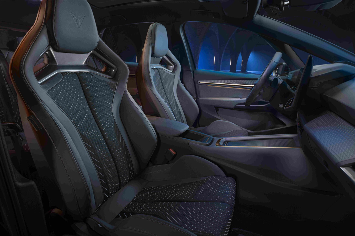 Cupra Born interieur toont sportieve donkere stoelen, modern dashboard en blauwe sfeerverlichting.