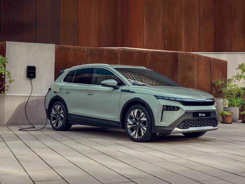 Green Skoda elroq aan het laden via een wallbox aan een villa