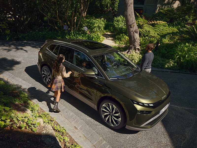 Groene skoda enyaq bovenaanzicht waar mensen net gaan instappen