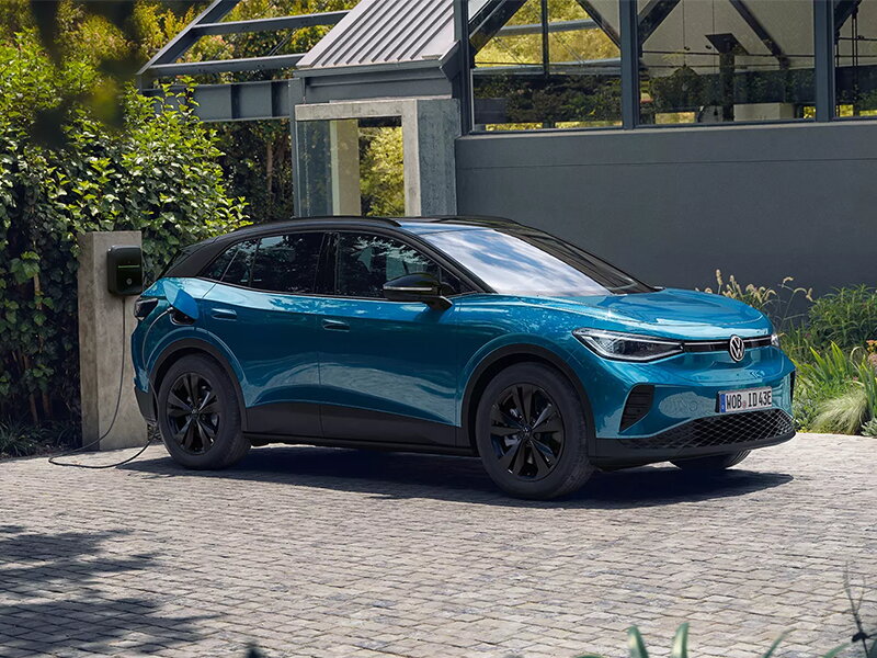 Blauwe elektrische VOlkswagen ID.4 aan het opladen op oprit via een wallbox