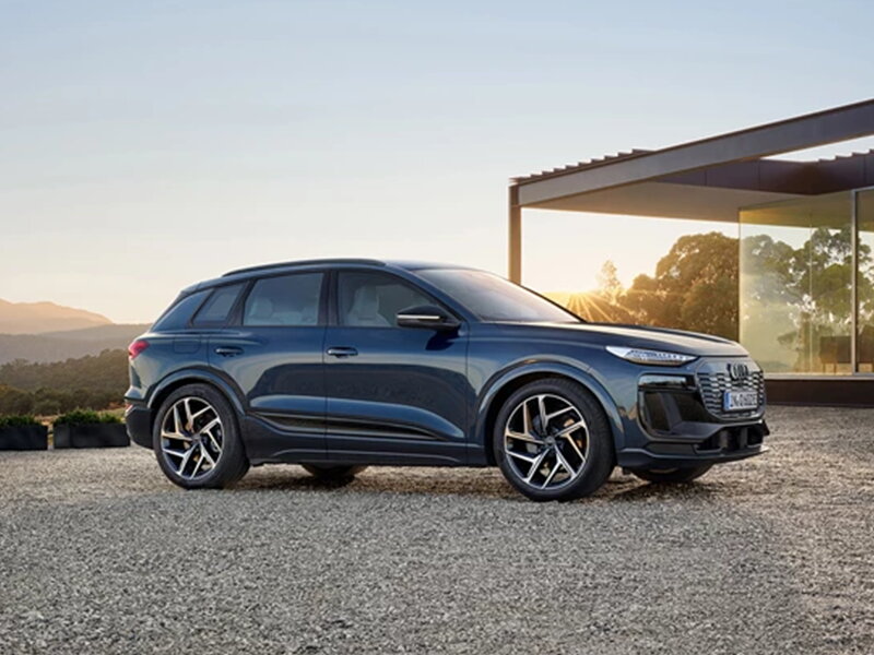 Audi Q6 e-tron blauw aan villa bij zonsondergang