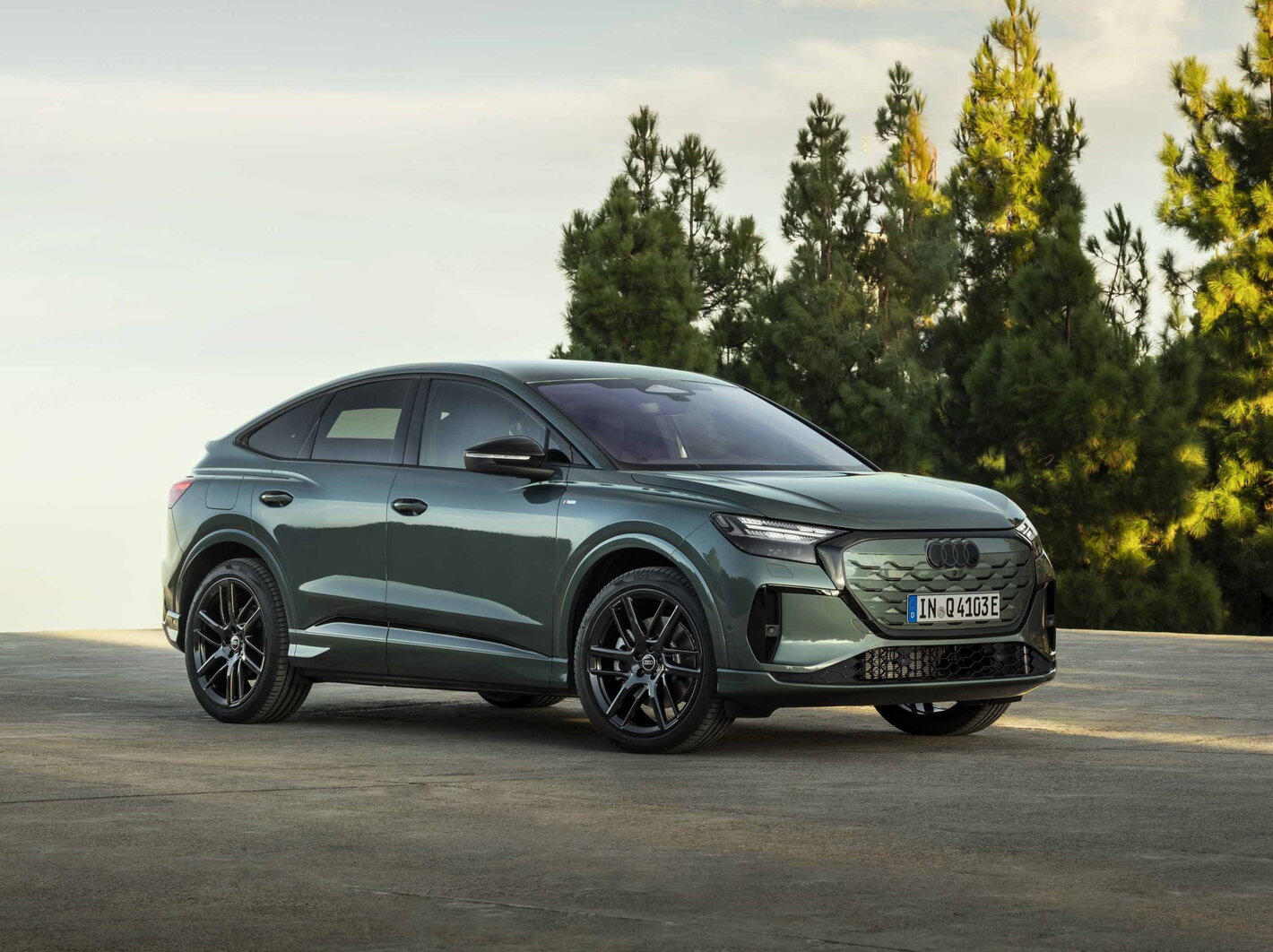 Zijaanzicht van een moderne donkergroene Audi Q4 e-tron Sportback SUV met zwarte velgen.
