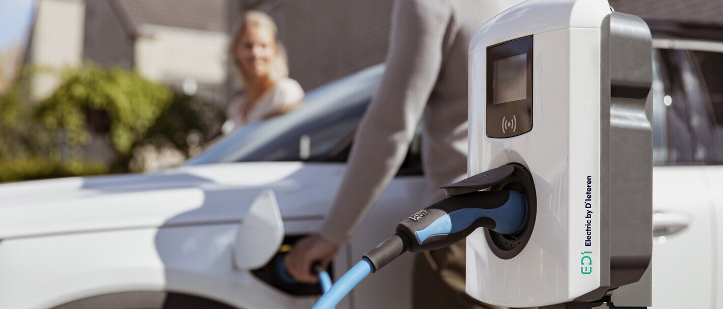 Een koppel staat op het punt om in hun elektrische wagen in te stappen die aan het laden is via hun laadpaal