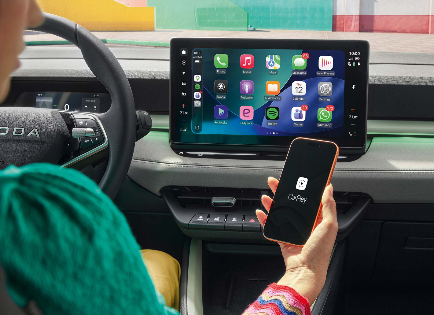 Vrouw in Skoda Epiq maakt verbinding met carplay met haar smartphone