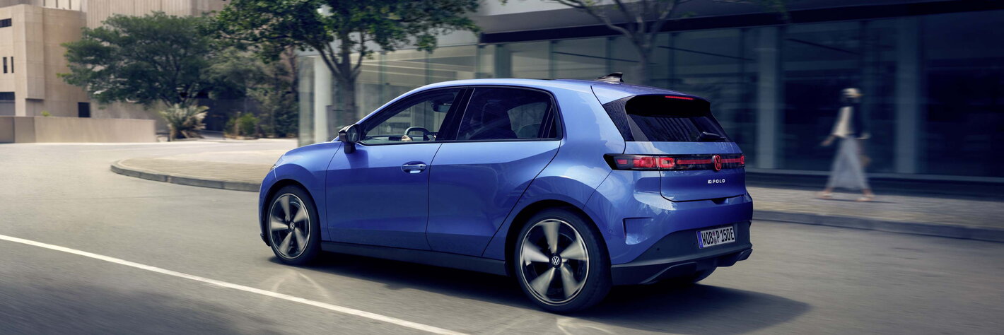 Blauwe Volkswagen ID.Polo rijdt dynamisch door de stad op een zonnige dag.