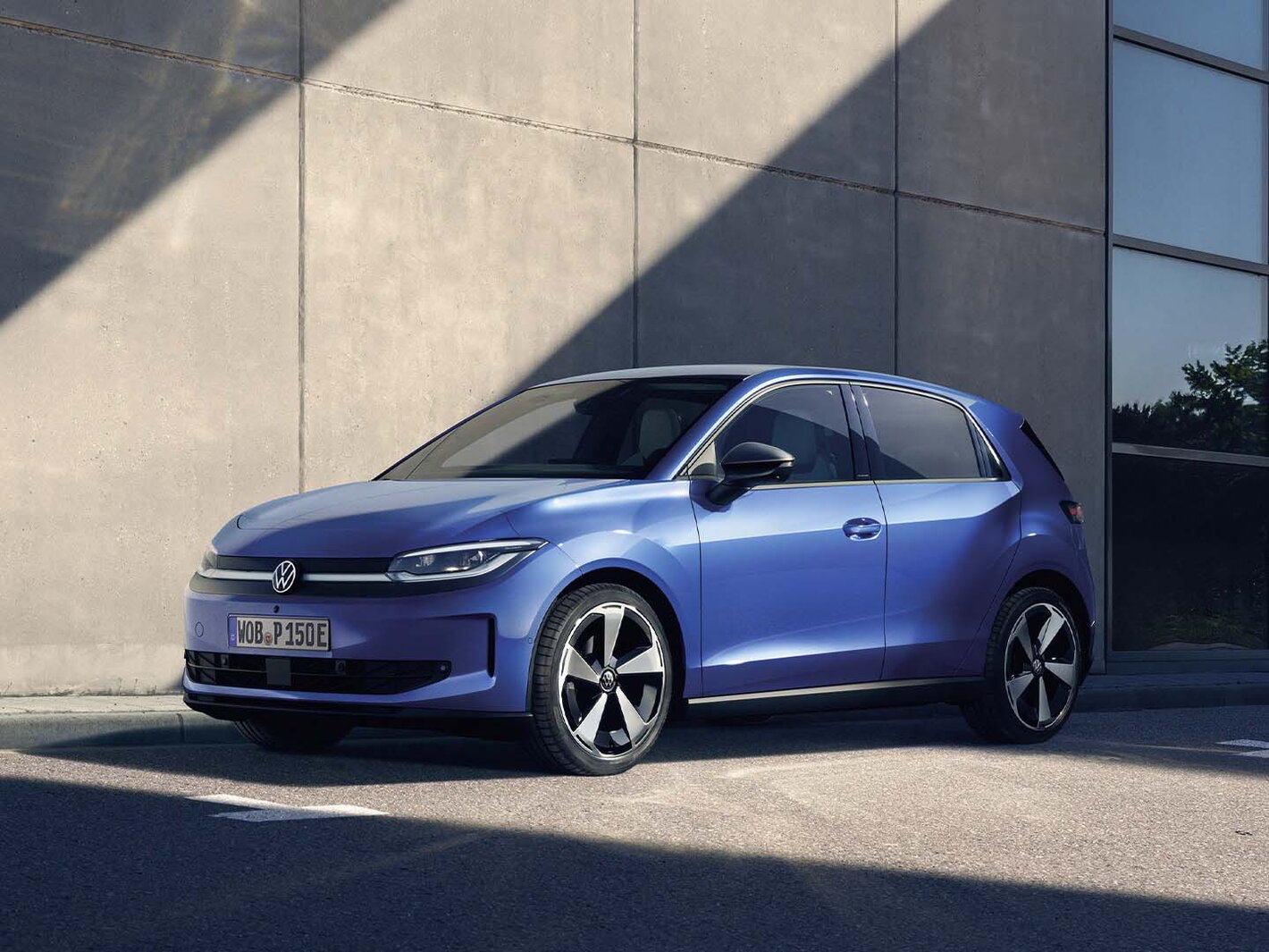 Blauwe Volkswagen ID.Polo staat geparkeerd bij een modern gebouw.