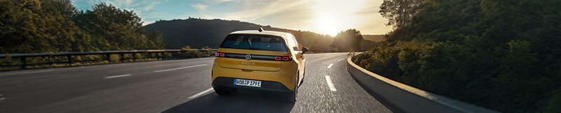 Gele Volkswagen ID.Polo rijdt bij zonsondergang op een bochtige weg