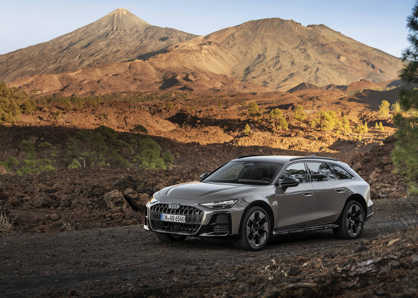 Audi A6 Allroad in donkergrijs voor imposante vulkaan, toont avontuurlijk design.